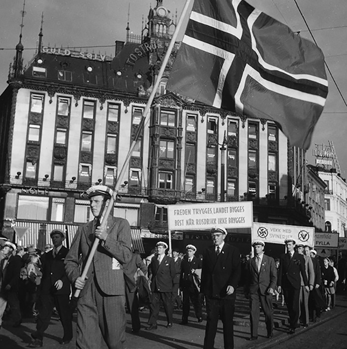 Menn med samme hvite hatter går i demonstrasjonstog med norsk flagg og plakater for avhold.