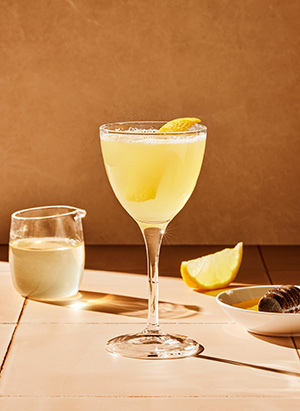 Stettglass med gul drikke og sitron og honning på bordet.