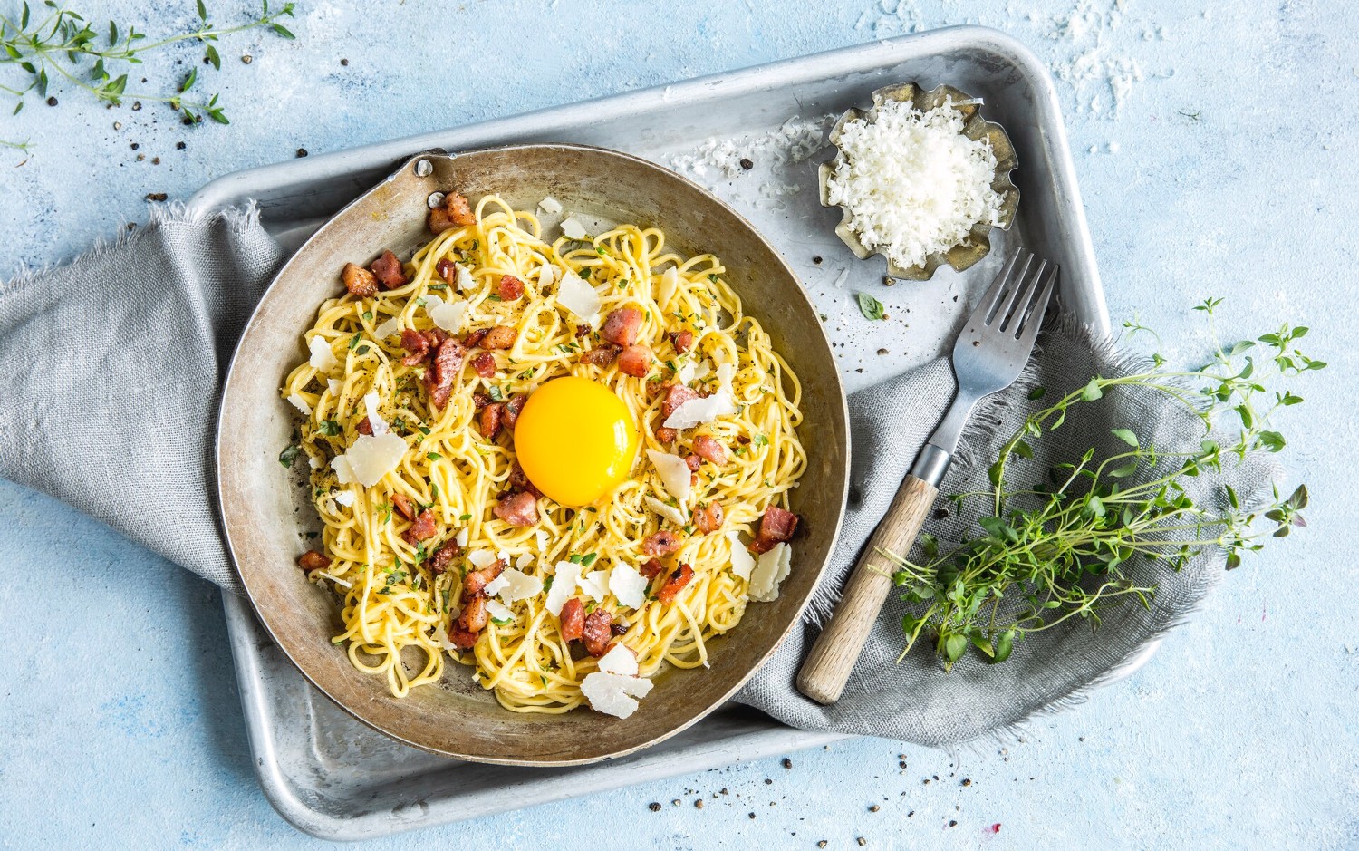 En tallerken med pasta carbonara med en eggeplomme i midten.