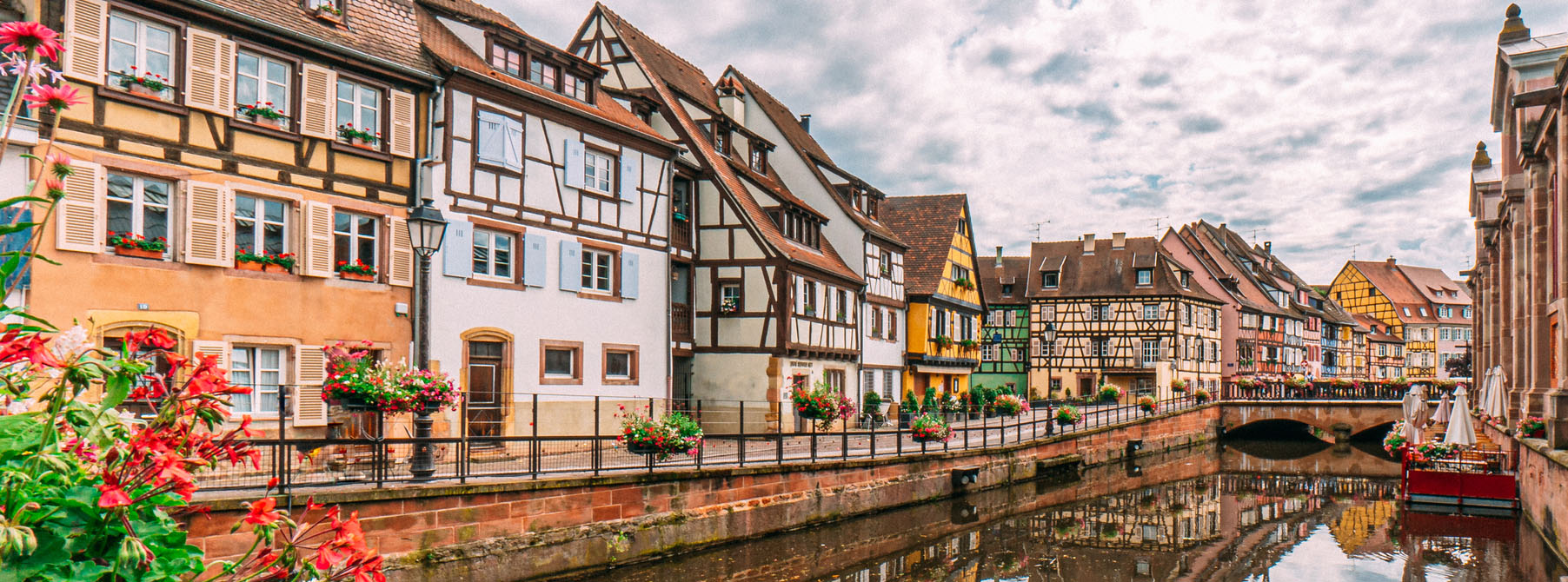 Typisk landsby i Alsace med fargerike hus ved en elv.