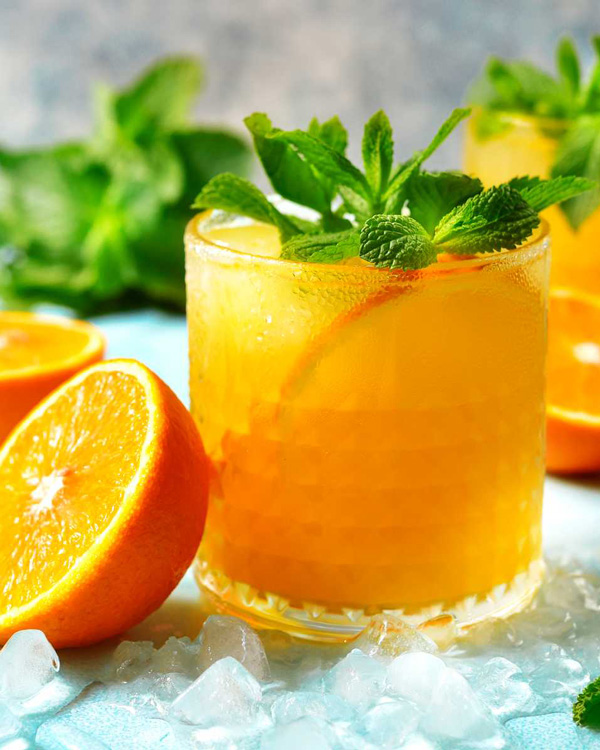 glass med isbiter og blandet drink med appelsin